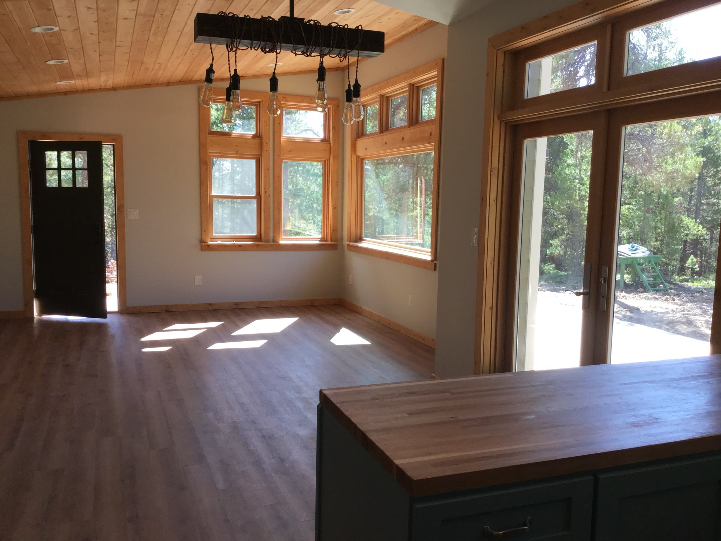 Cabin interior with a wood plank ceiling, hardwood floor, and glass doors into the trees