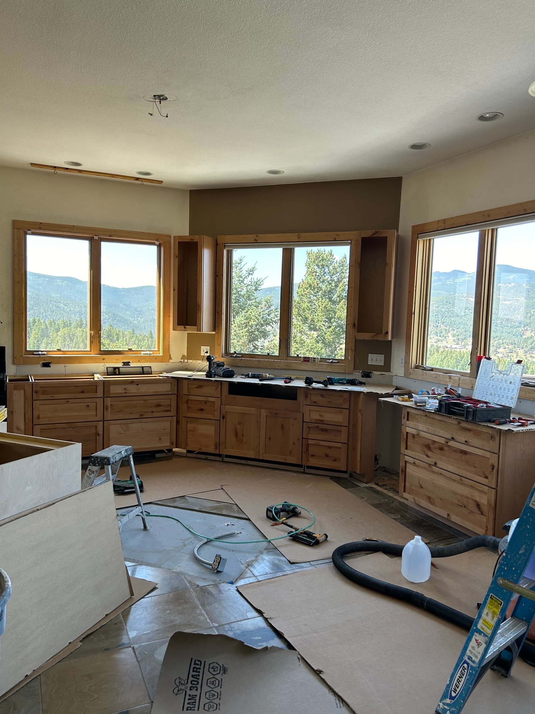 Knotty pine base cabinets being installed under a wall of windows