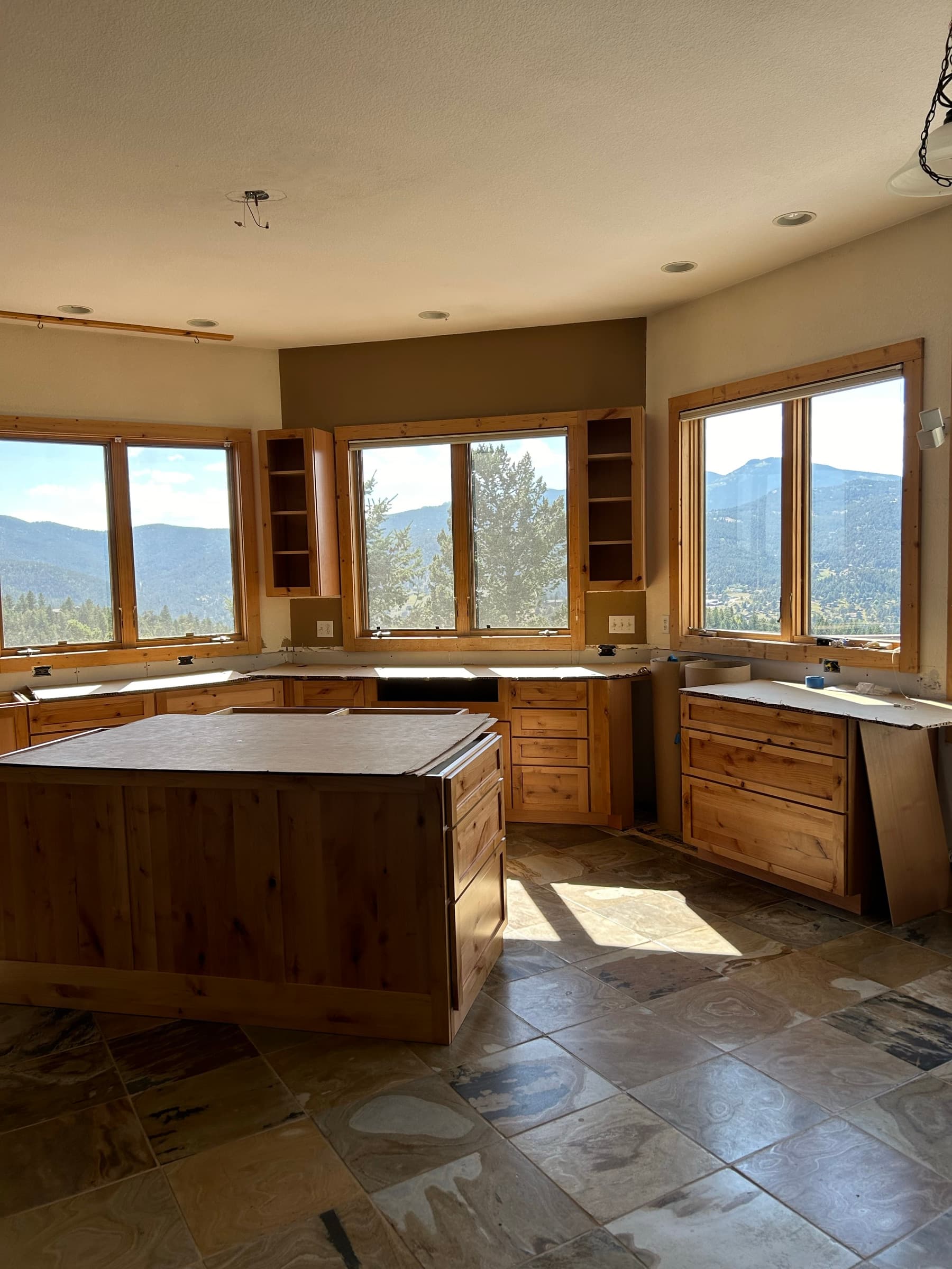 Kitchen remodel in progress with pine cabinets and stone tile floors
