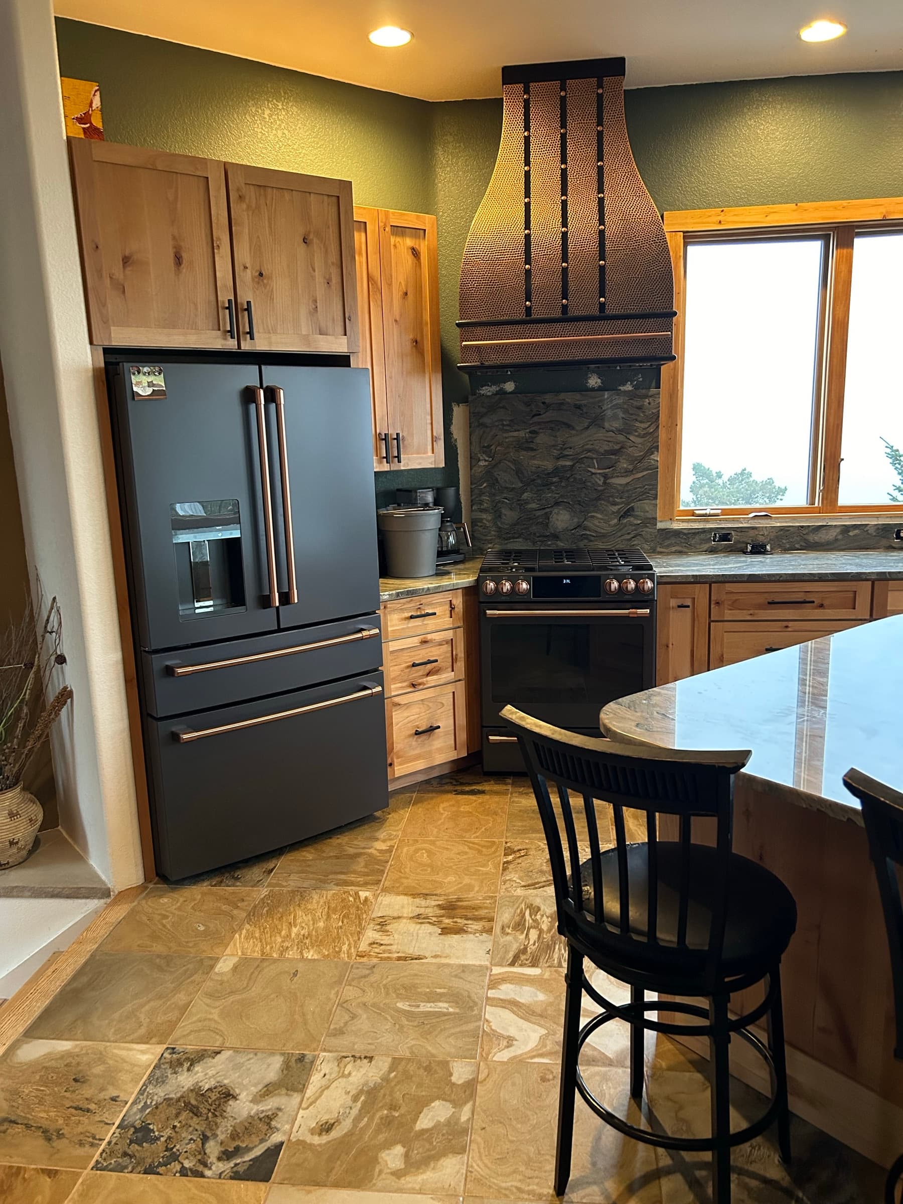 Hammered copper range hood over a black range with copper knobs