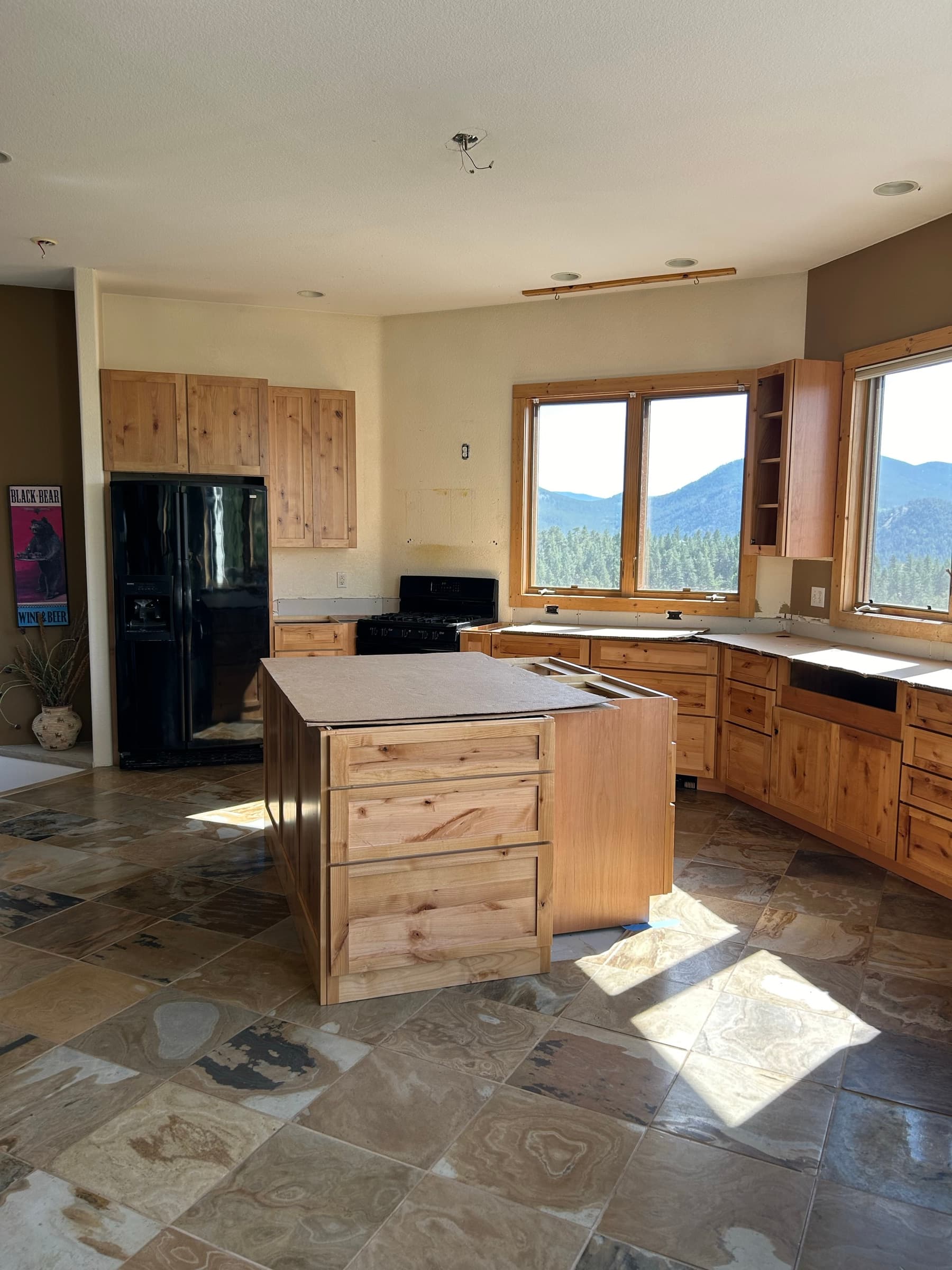 Kitchen remodel in progress with pine cabinets and a view of forested hills