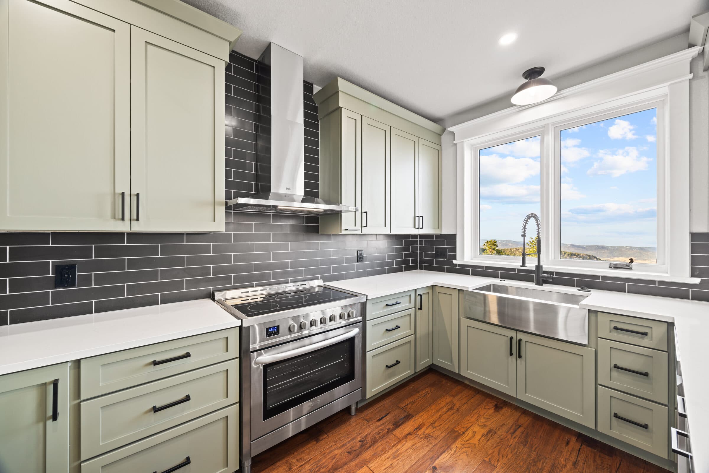 Sage kitchen with dark subway tile, a stainless range, and a farmhouse sink under a window