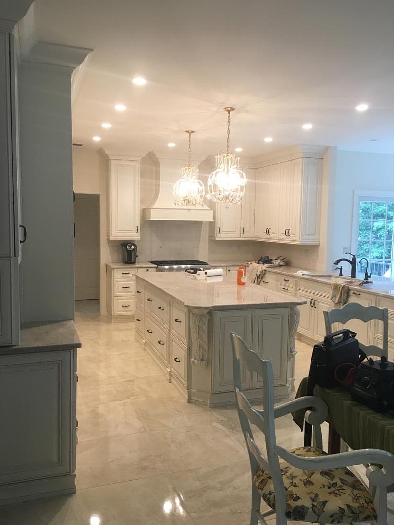 White kitchen with ceiling-height cabinets, granite counters, and a chandelier