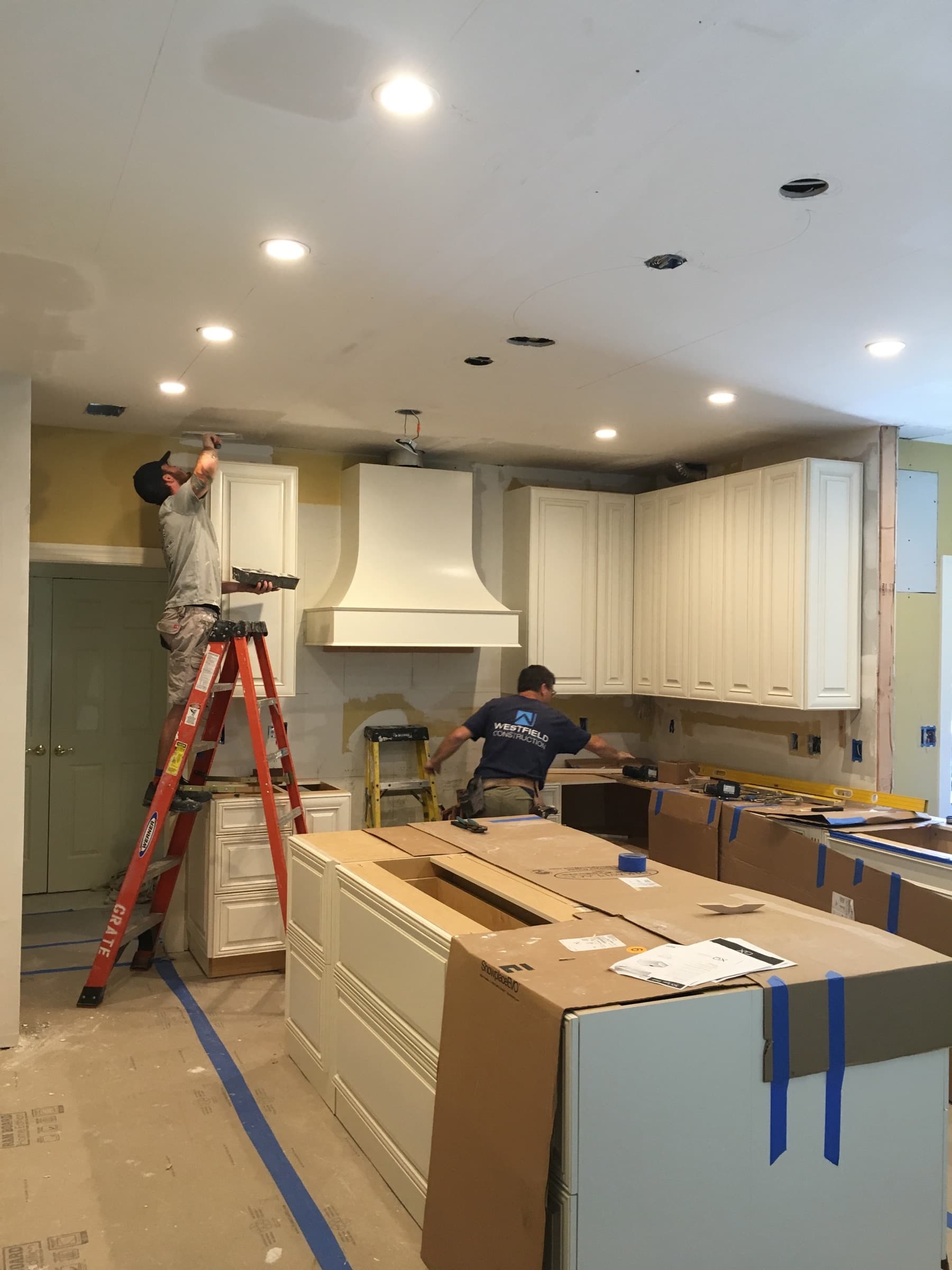 Crew installing cabinets and finishing the ceiling on a kitchen remodel