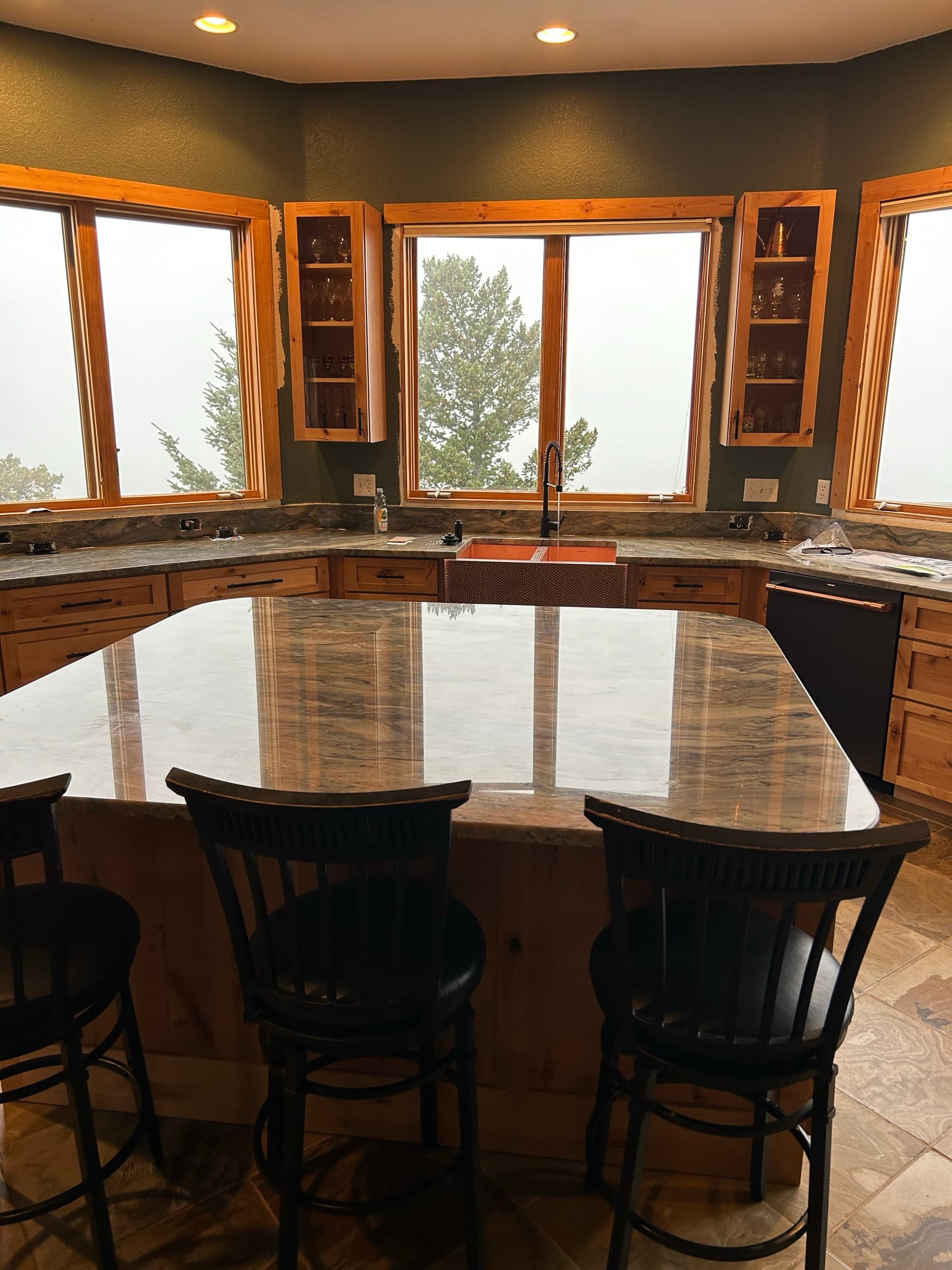 Finished kitchen island with swirling stone, knotty pine cabinets, and a copper farmhouse sink