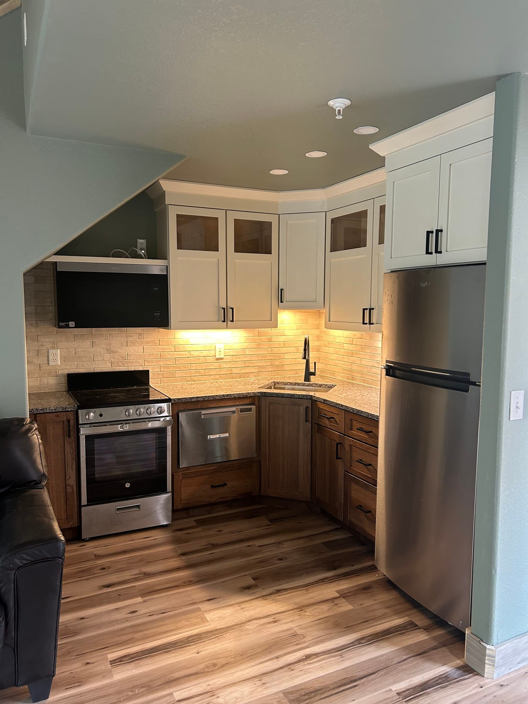 Two-tone kitchen tucked under a sloped ceiling, with wood lower cabinets and cream uppers