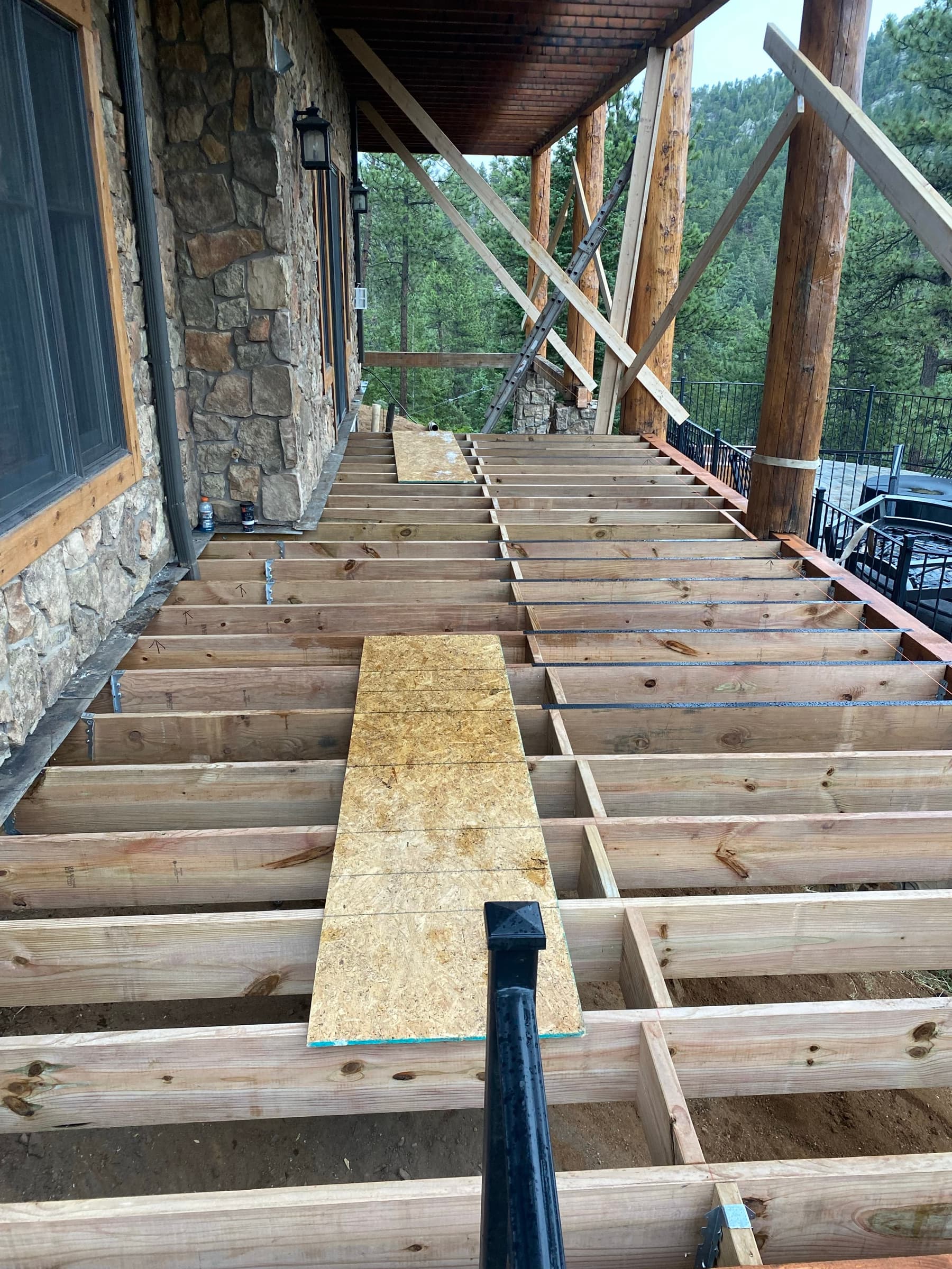Exposed deck joists with flashing tape on a stone house