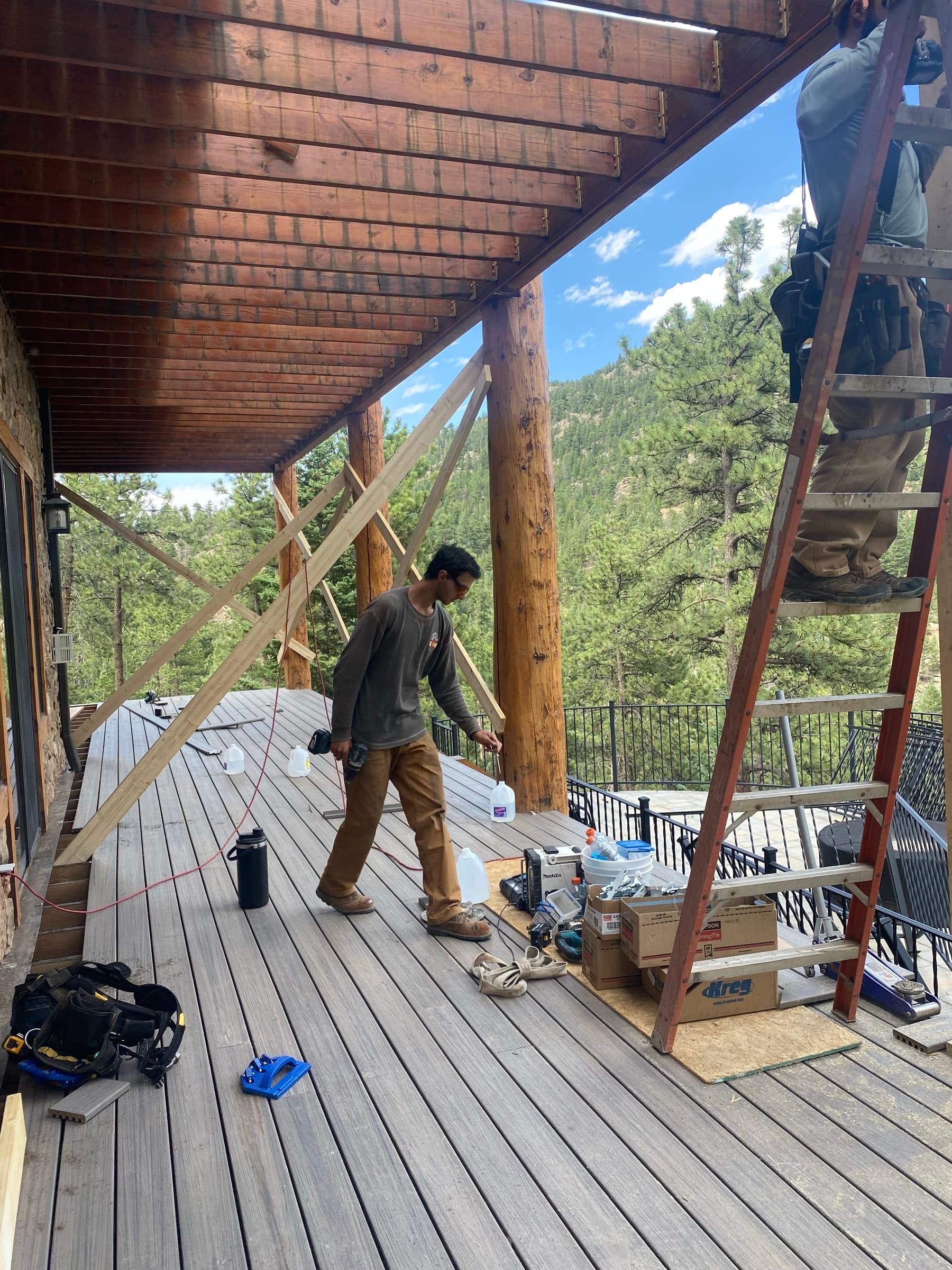 Composite deck going down on a log-and-stone house overlooking a forested valley