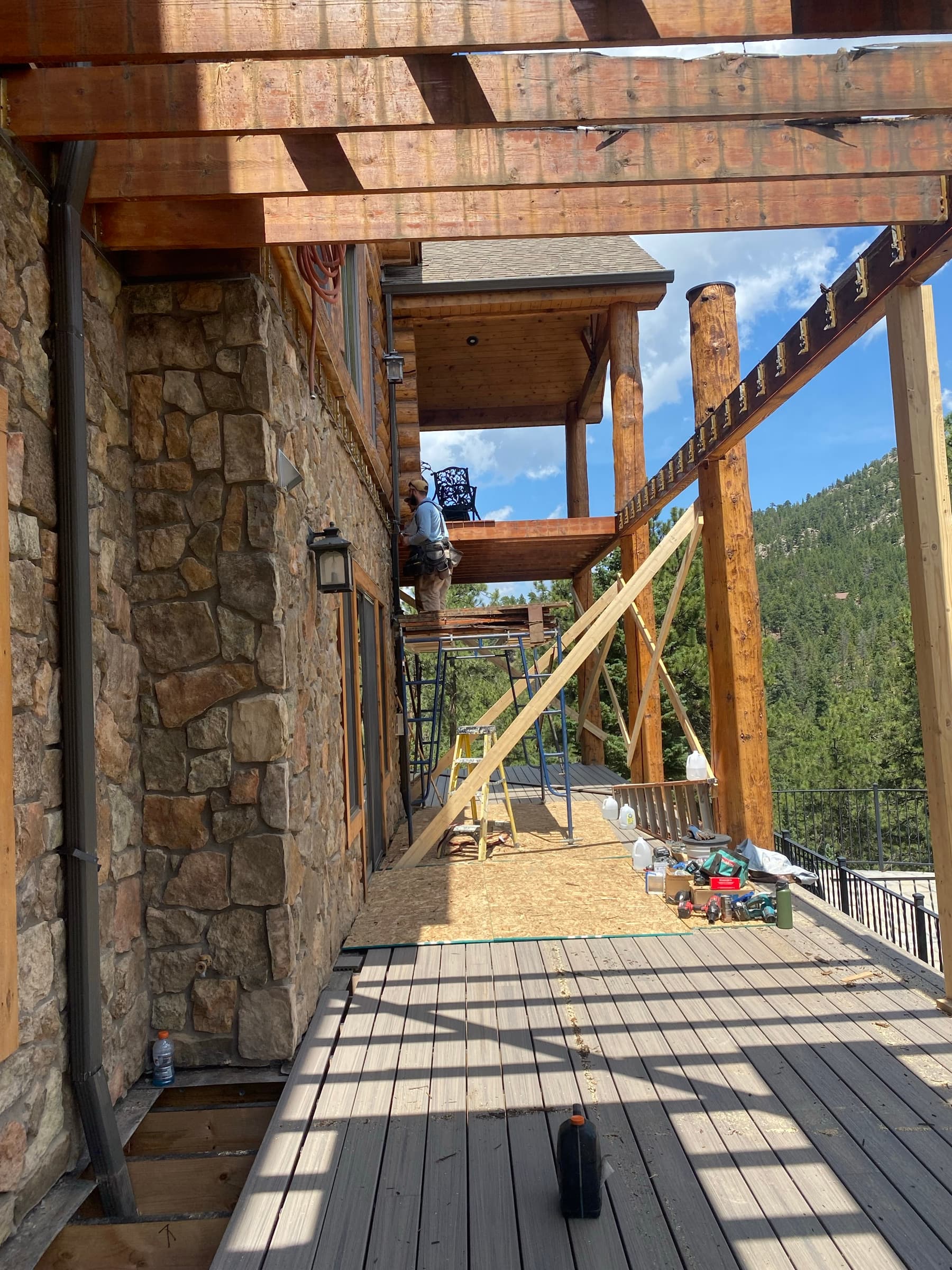 Log columns, stone veneer, and composite decking during construction