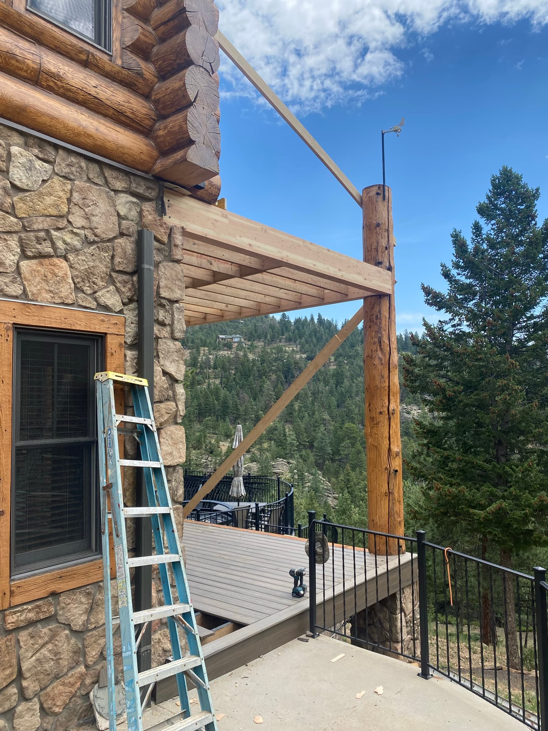 New deck framing tied into a log-and-stone house